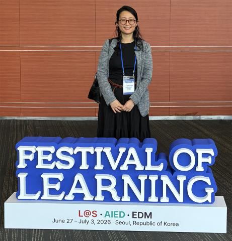 Jonna Lee standing behind a sign that reads "Festival of Learning."